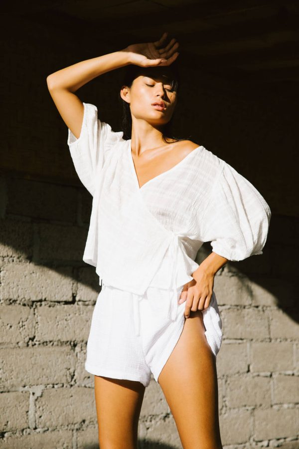 woman wearing the Maddie Shorts in White Textured paired with the Ella Wrap Top by the brand The Bare Road