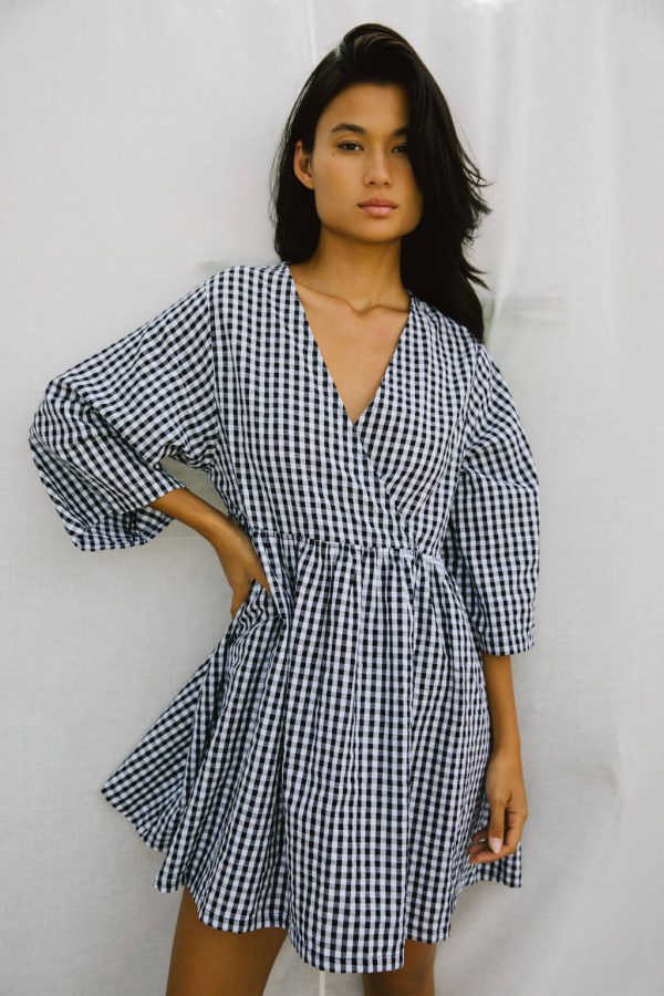 woman wearing the Holiday Wrap Dress in Black Gingham by the brand The Bare Road