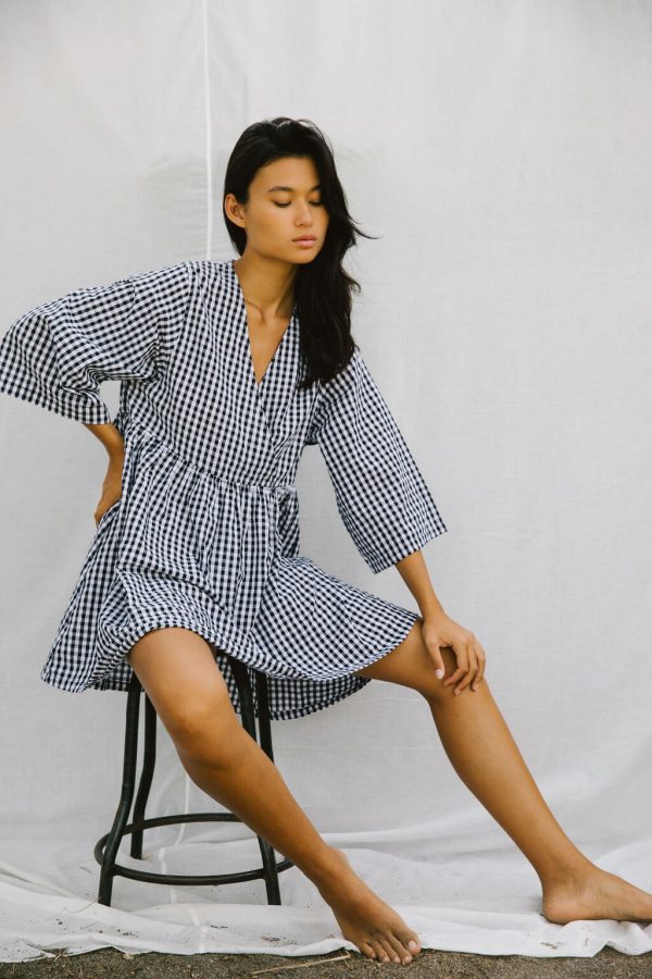 woman wearing the Holiday Wrap Dress in Black Gingham by the brand The Bare Road