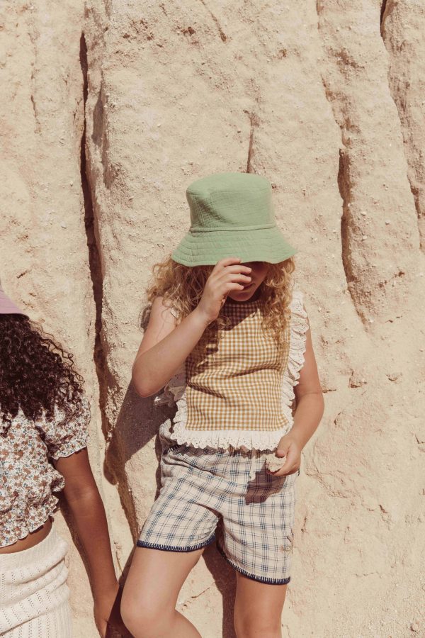 the organic cotton Mona Top in Mustard Vichy paired with the Bucket Hat in Dryed Green by the brand LiiLU