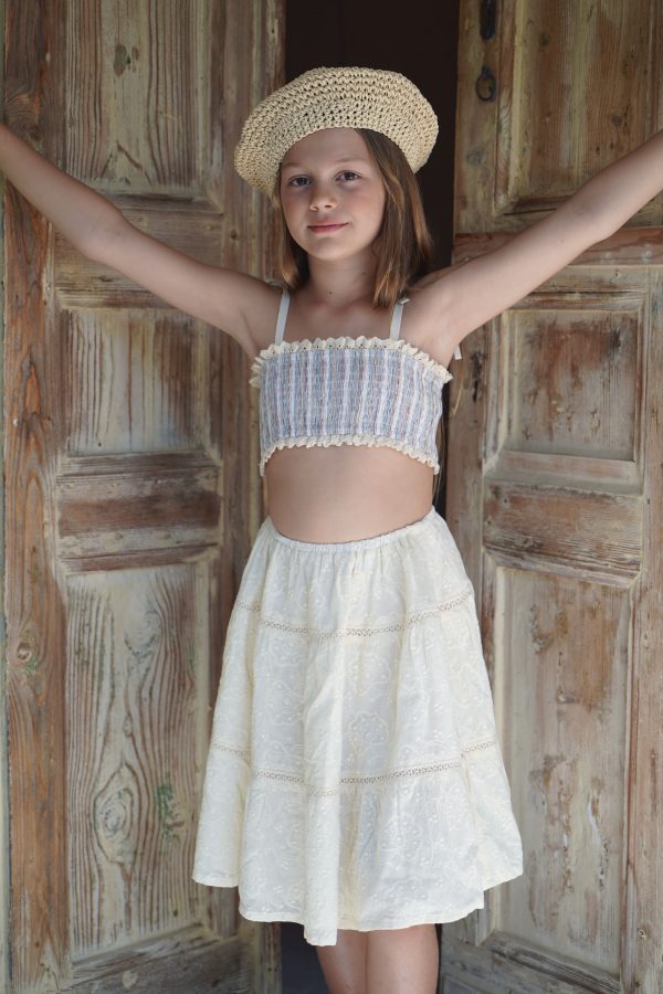 girl wearing the Baia Skirt in cotton Creme Broderie, paired with the Agnes Swim Set in Sicilian Stripe by the Australian brand House of Paloma, curated by Morsel Store