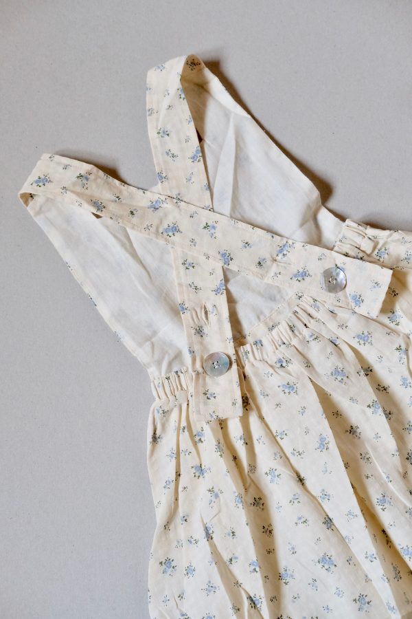 flatlay of the Fiona Pinafore Dress in cotton Fleur Bleue fabric by the sustainable brand House of Paloma, showing the cross over staps in the back, curated by Morsel Store