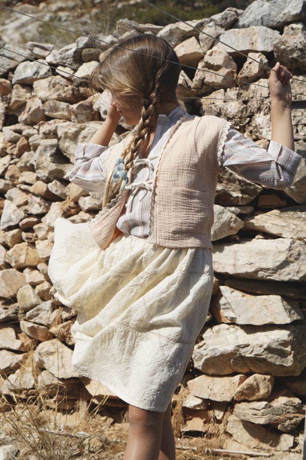 girl wearing the Pasquelina Vest in muslin Peach Sorbet fabric paired with the Baïa Skirt in Creme Broderie and the Jule Tunic in Sicilian Stripe by the sustainable brand House of Paloma, curated by Morsel Store