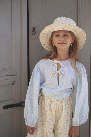 girl wearing the Oracle Blouse in Pique Nique gingham fabric paired with the Hydra Sun Hat and Yolanda Pant in a floral Fleur Bleue fabric, by the sustainable brand House of Paloma and curated by Morsel Store