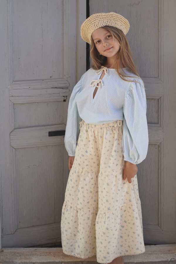 girl wearing the Oracle Blouse in Pique Nique gingham fabric paired with a raffia hat and the Yolanda Pant in a floral Fleur Bleue fabric, by the sustainable brand House of Paloma and curated by Morsel Store