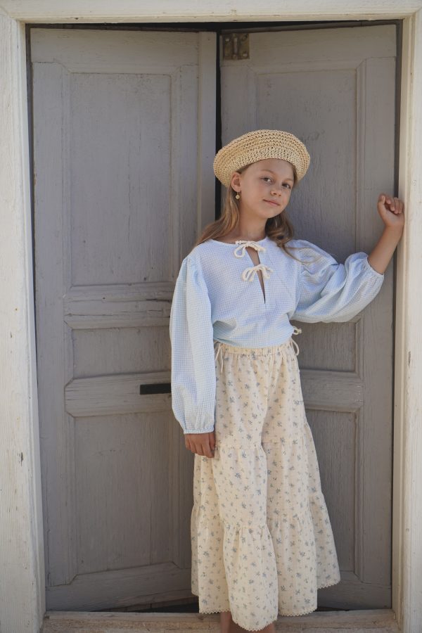 girl wearing the Oracle Blouse in Pique Nique gingham fabric paired with a raffia hat and the Yolanda Pant in a floral Fleur Bleue fabric, by the sustainable brand House of Paloma and curated by Morsel Store