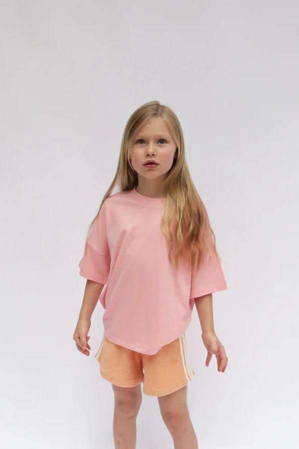 girl wearing the Oversized Tee in Bubblegum Pink paired with the Racer Shorts in Peach by the brand Summer and Storm, curated by Morsel Store