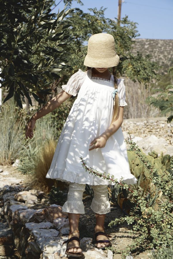 girl wearing the Zadie Pant in Creme Broderie, paired with the Sirene Blouse, Frida Apron Dress & Raffia Hat, by the sustainable brand House of Paloma, curated by Morsel Store