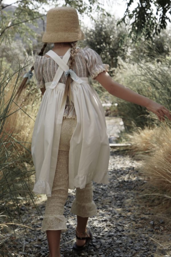 girl wearing the Zadie Pant in Creme Broderie, paired with the Sirene Blouse, Frida Apron Dress & Raffia Hat, by the sustainable brand House of Paloma, curated by Morsel Store