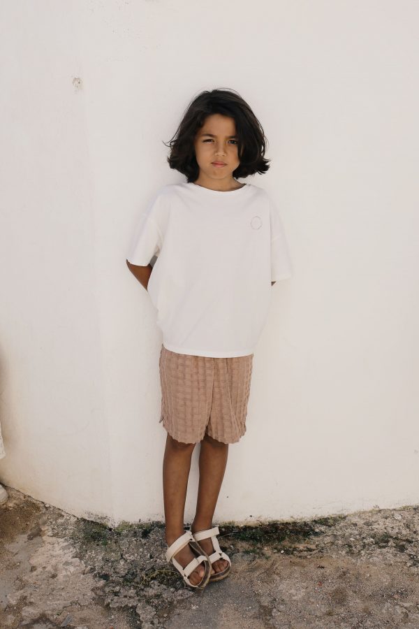 boy wearing the Ben Bermuda in Chestnut organic waffle cotton, paired with a white tee by the sustainable brand Liilu, curated by Morsel Store, located on Mallorca