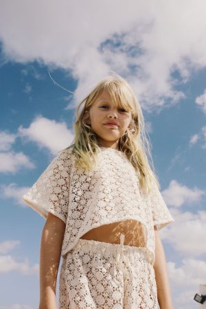 girl wearing the Crochet T-shirt in Ecru organic cotton paired with the matching Crochet Pant by the sustainable brand Liilu, curated by Morsel Store, located on Mallorca