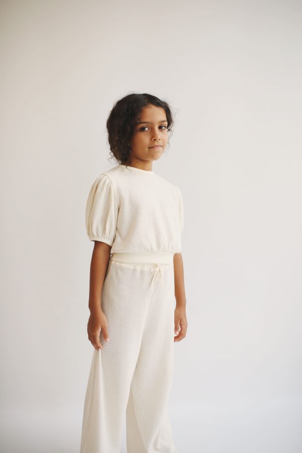 girl wearing the Jala Blouse in Ecru organic cotton paired with the matching Sweta Pant by the sustainable brand LiiLu, curated by Morsel Store, located on Mallorca