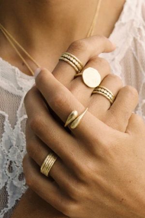 woman wearing the Filippa Ring, Luna Ring & Mila ring in gold by the sustainable jewellery brand Agapé Studio, curated by Morsel Store