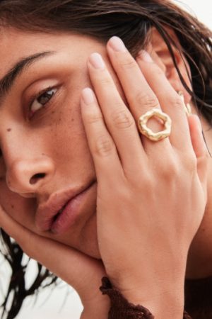 woman wearing the Nura Ring in gold by the sustainable jewelry brand Agapé Studio (now Agapée), curated by Morsel Store