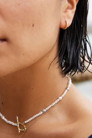 woman wearing the Oia Choker Necklace in white and gray pearls with the Gina Earrings in gold by the sustainable jewelry brand Agapé Studio (now Agapée), curated by Morsel Store