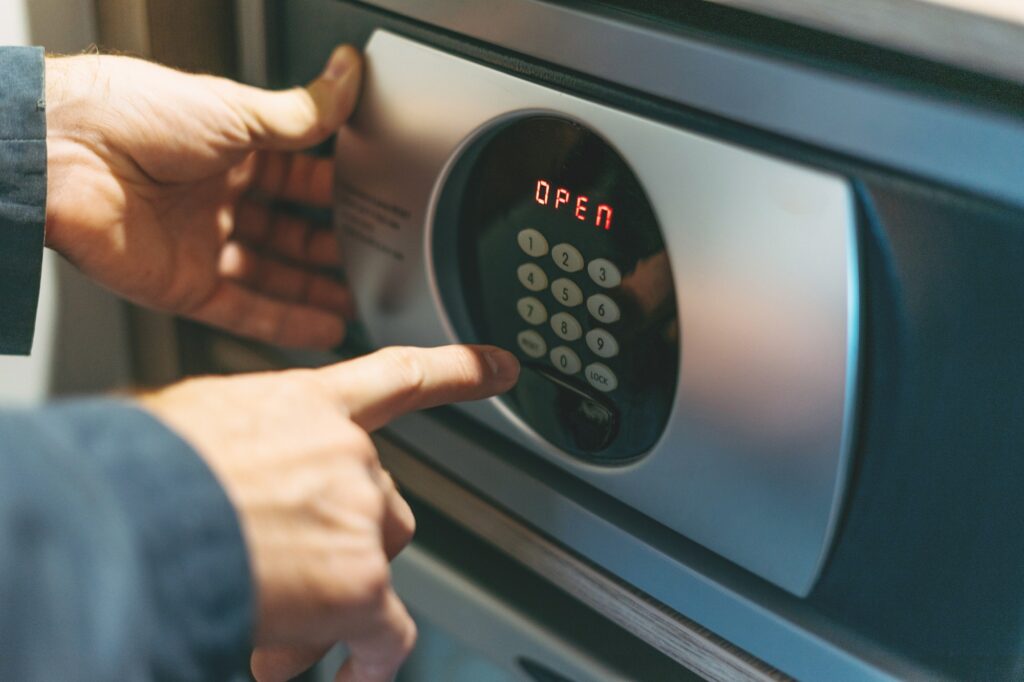 Adult man in blue jacket uses safe in the hotel room