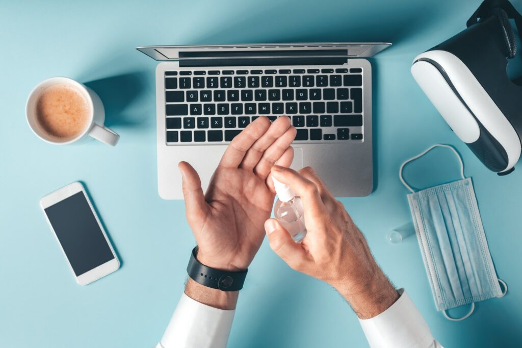 Stay safe, businessman using disinfectant spray in office while working on laptop computer