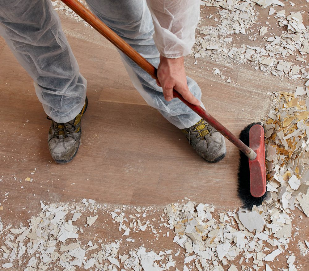 Builder sweeping the floor after renovation