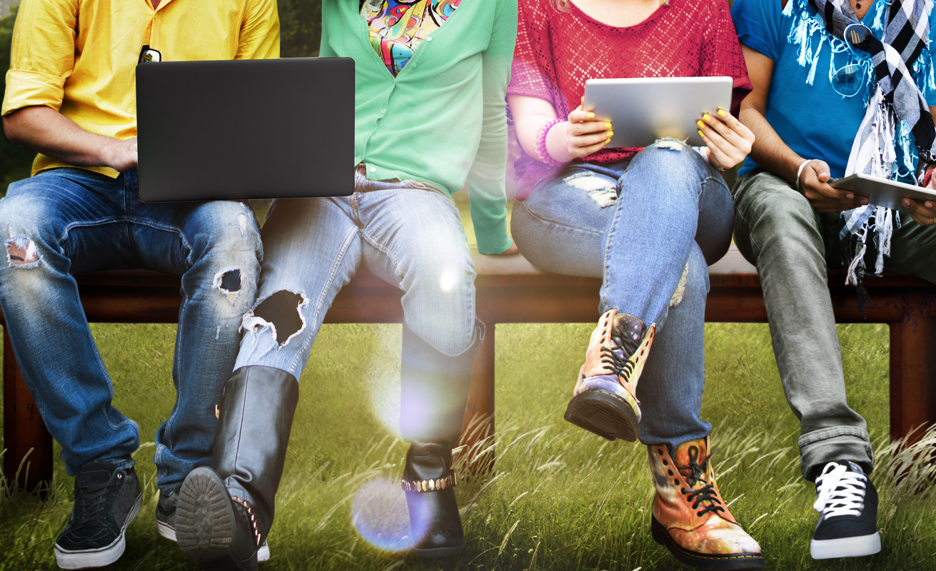 Students sitting on a bench using laptops