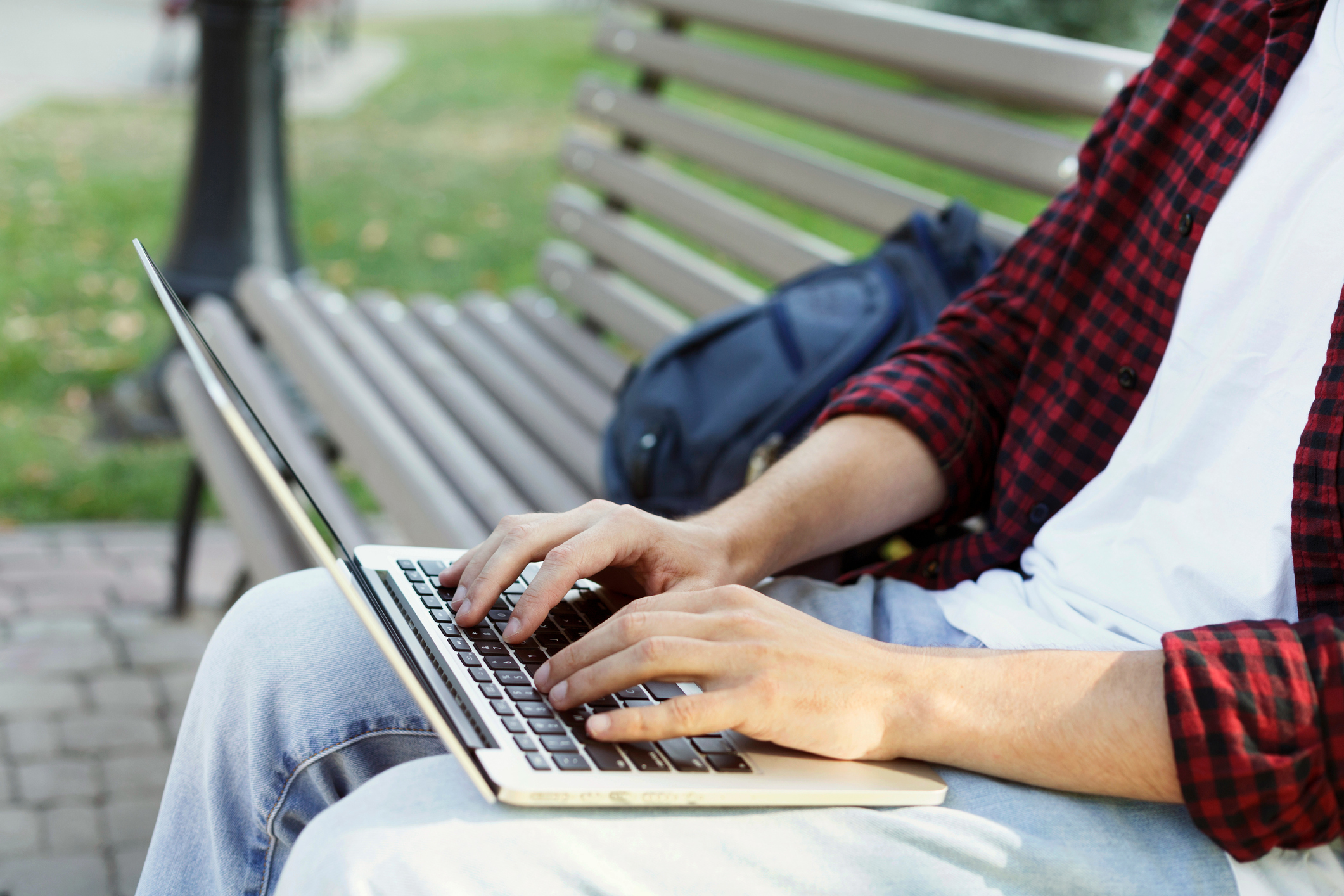 Male hands typing on laptop closeup outdoors