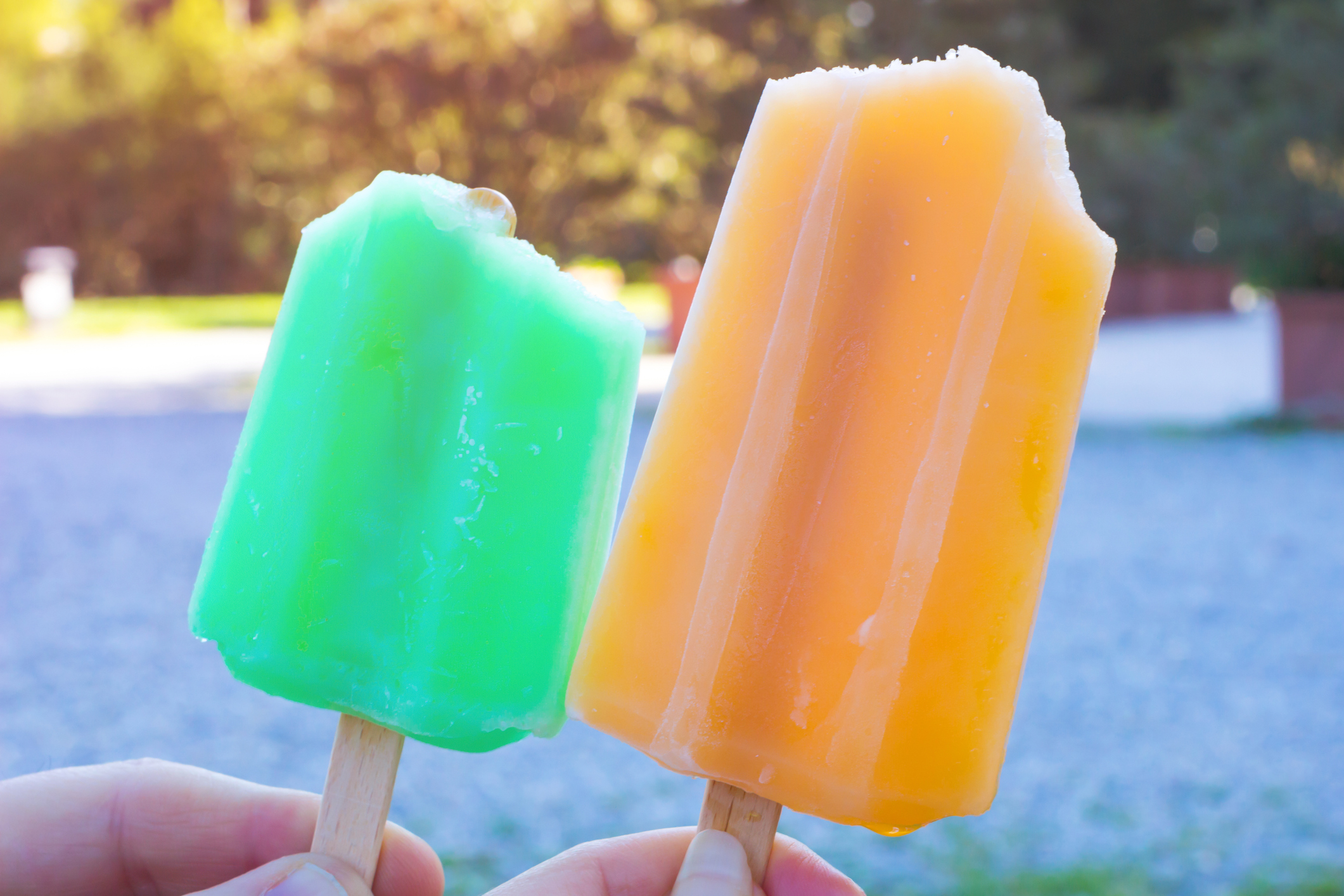 young man and young girl having an green and orange appetizing ice cream in the summer park.