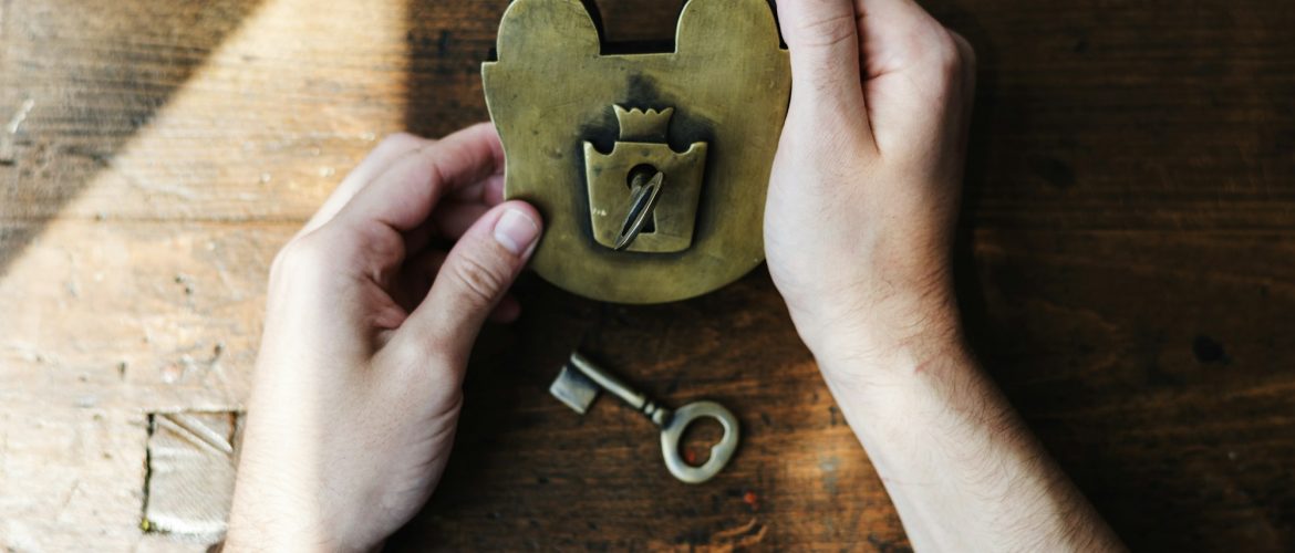 Hands Holding Unlock Padlock and Key on Wooden Table