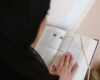 person in black hijab holding white printer paper