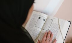 person in black hijab holding white printer paper