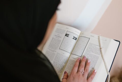 person in black hijab holding white printer paper