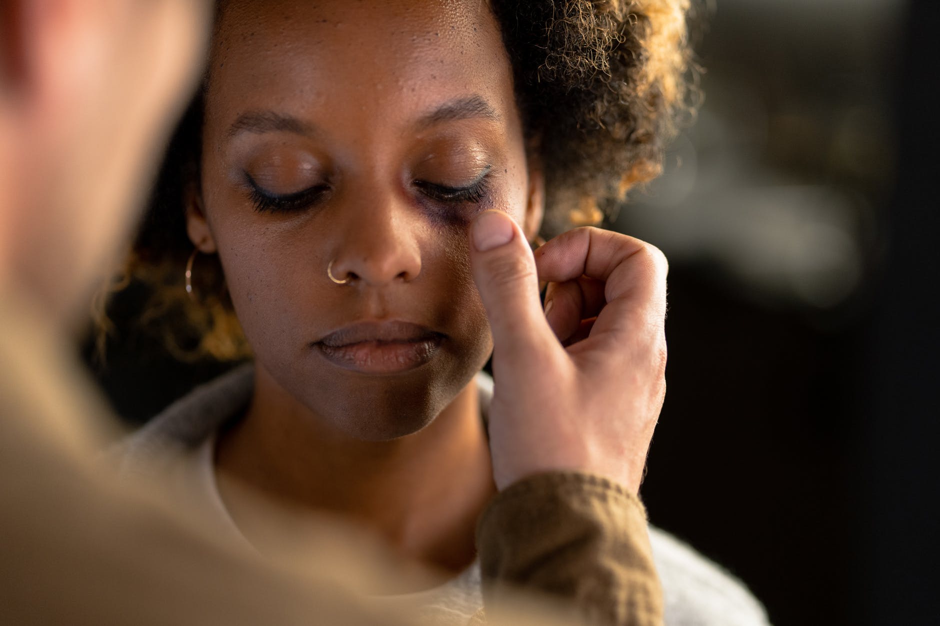 a person touching a woman s eye with a bruise