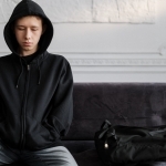 man in black zip up hoodie sitting on purple sofa