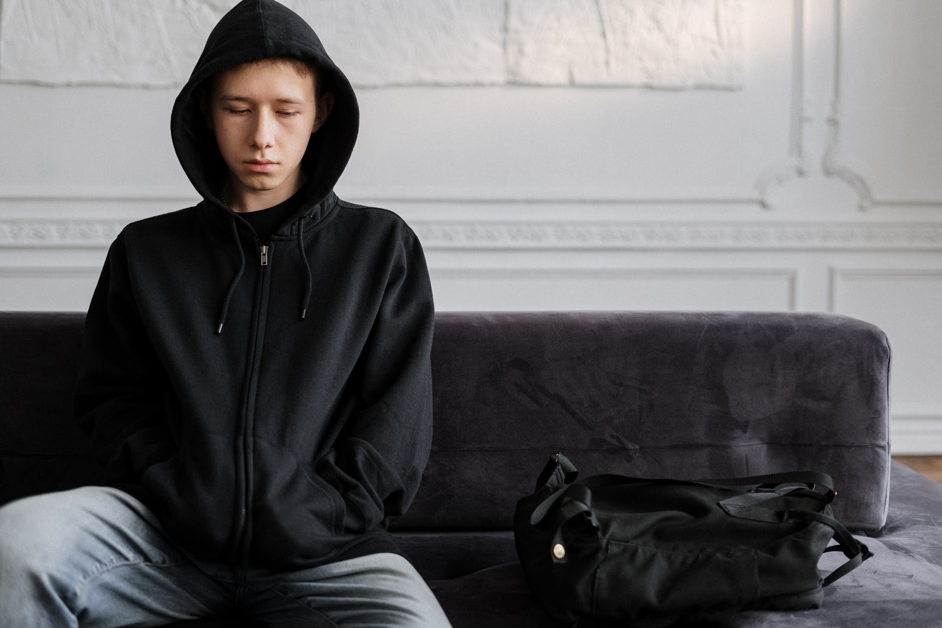 man in black zip up hoodie sitting on purple sofa