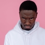angry black man in hoodie against light pink background
