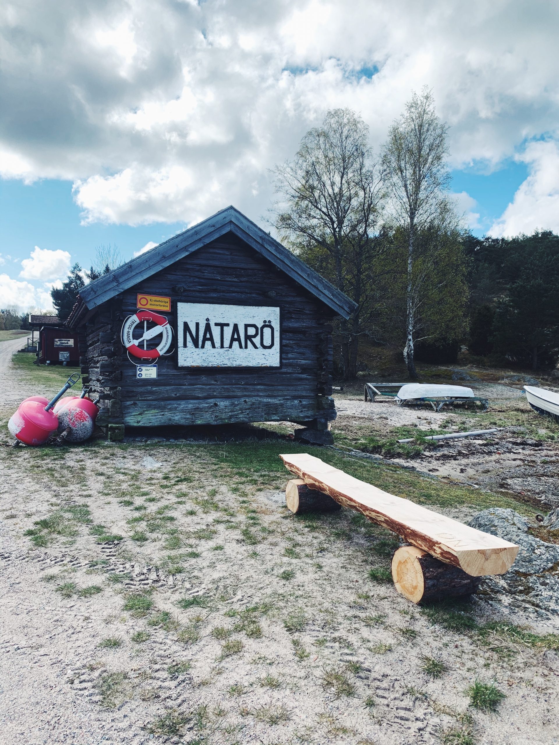 Bild på det första en går förbi vid ankomst till Ångbåtsbryggan på Nåttarö. En gammal stuga med livboj och skylt som lyder "Nåtarö", den tidigare stavningen av vår populära skärgårdsö.