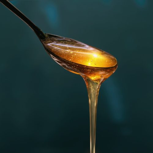 Delicious honey pours out of the spoon close up