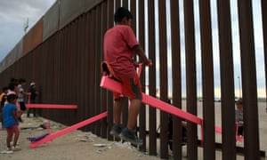 Children in Mexico play on the border fence seesaws.