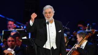 Placido Domingo singing on stage with an orchestra behind him