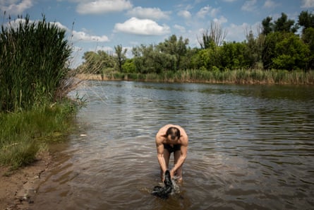 Slava Volodymyrovich, a soldier in the Donbas battalion, washes some of his clothes in the river in Sloviansk, June 2022