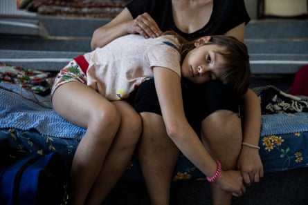 Victoria Soldatova lies on the lap of her mother, Oksana Soldatova, at a shelter in Dnipro