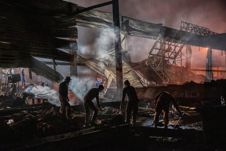 Volunteers and firefighters work to extinguish a fire at a shopping centre after a rocket attack in Kremenchuk, June 2022