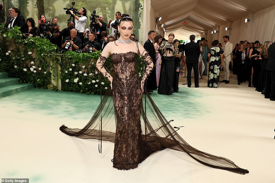 Social media star Emma Chamberlain wore a brown sheer gown with a dramatic train and branch-like sleeves, adding a diamond choker and smokey brown eye makeup