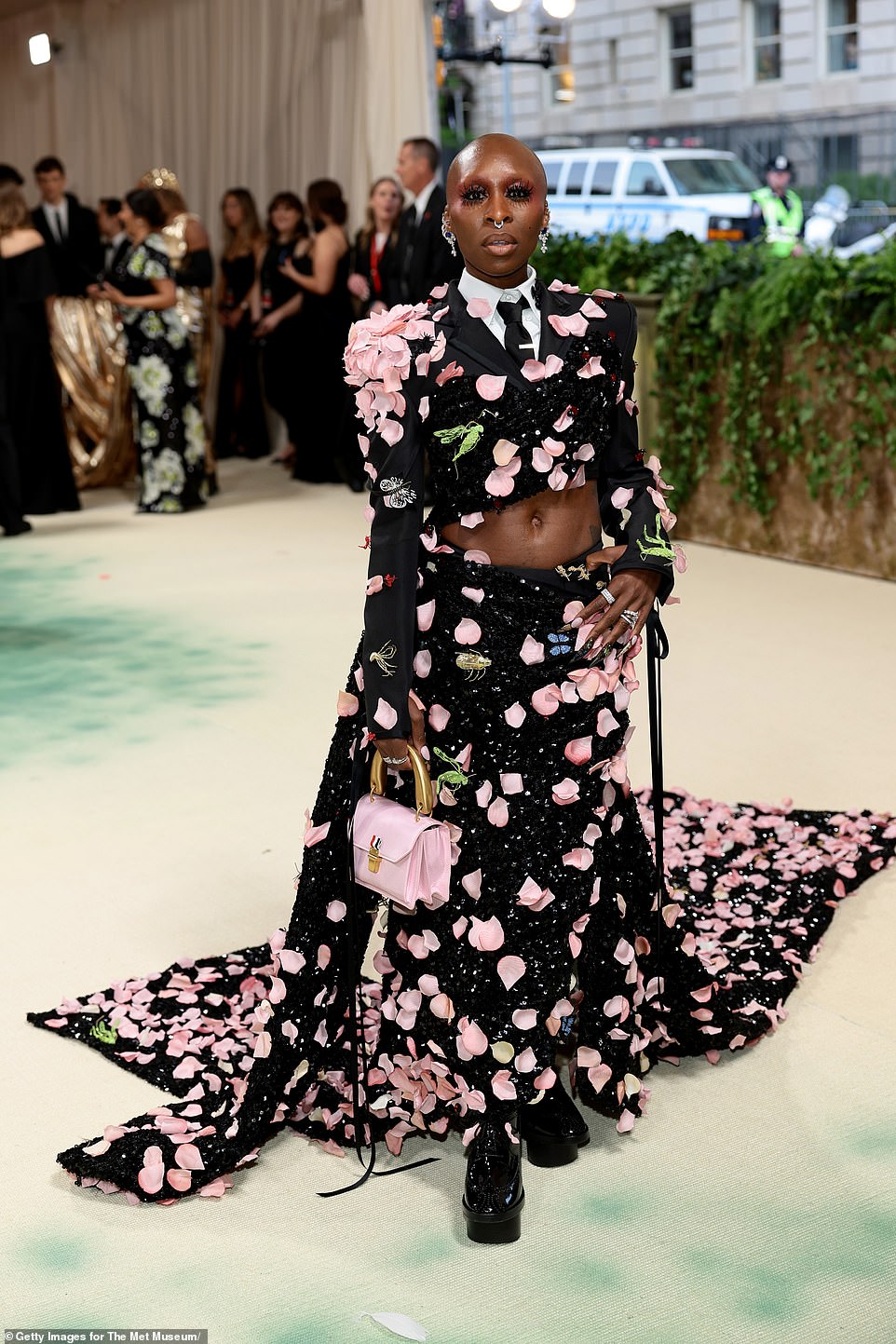 Cynthia Erivo dazzled in a statement gown - consisting of a black jacket and matching maxi skirt with pink rose petals attached to it, along with butterfly and different type of faux insects also attached; she is wearing Thom Browne
