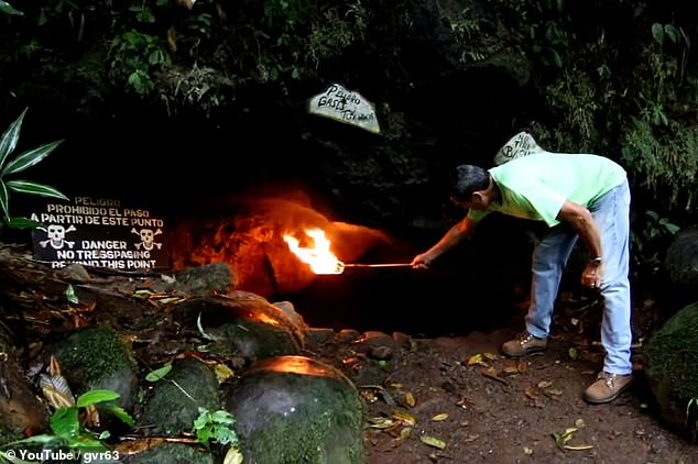 Visitors to the Cave of Death demonstrate its potency by holding a lit torch to the entrance. Note the warning sign adorned with deathly skulls and crossbones saying: 'Danger! No trespassing beyond this point'