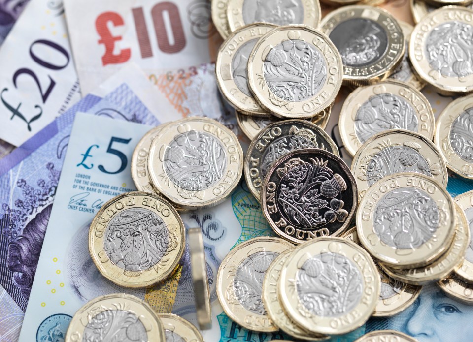 Hand holding a fan of British twenty-pound notes.