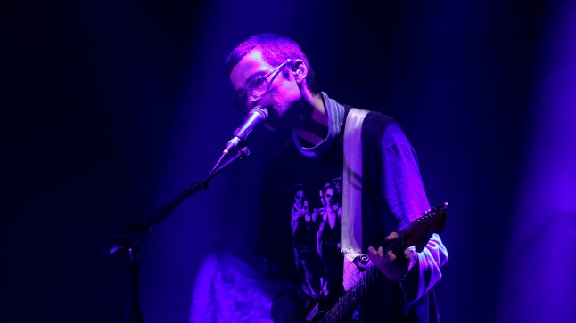 Zachary Cole Smith of DIIV singing on stage and playing guitar