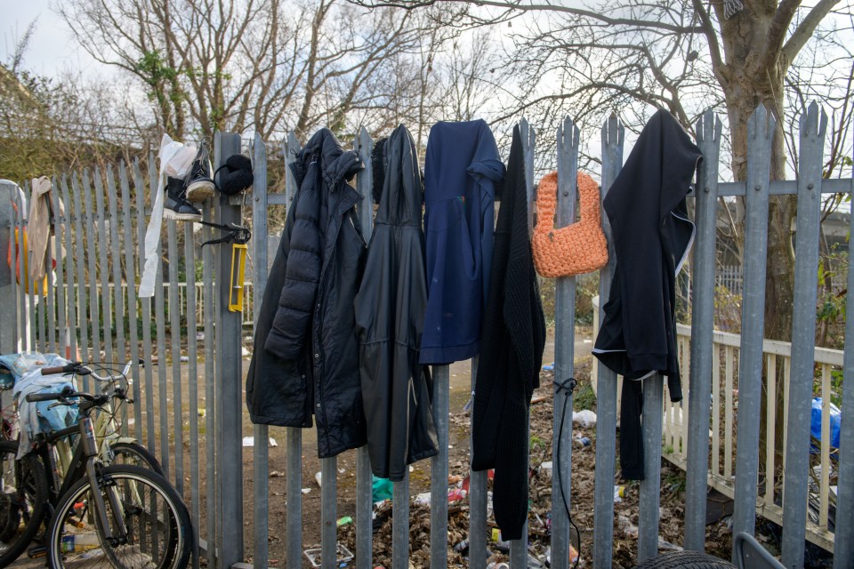 Clothing and footwear hanging on a fence.