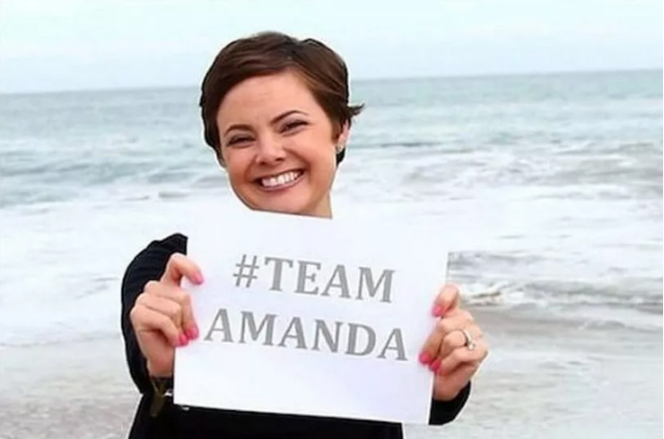 Amanda Riley, the main protagonist of the podcast Scamanda, holding a sign that says #TeamAmanda.