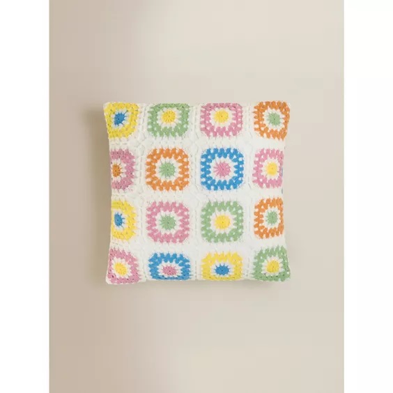 Crochet cushion with pastel granny squares.