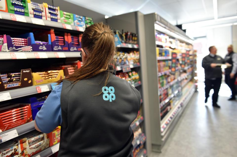 A Co-op employee stocking shelves in a supermarket.