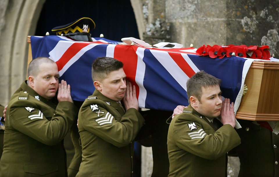 Soldiers carry a coffin draped with a Union Jack flag at a funeral.